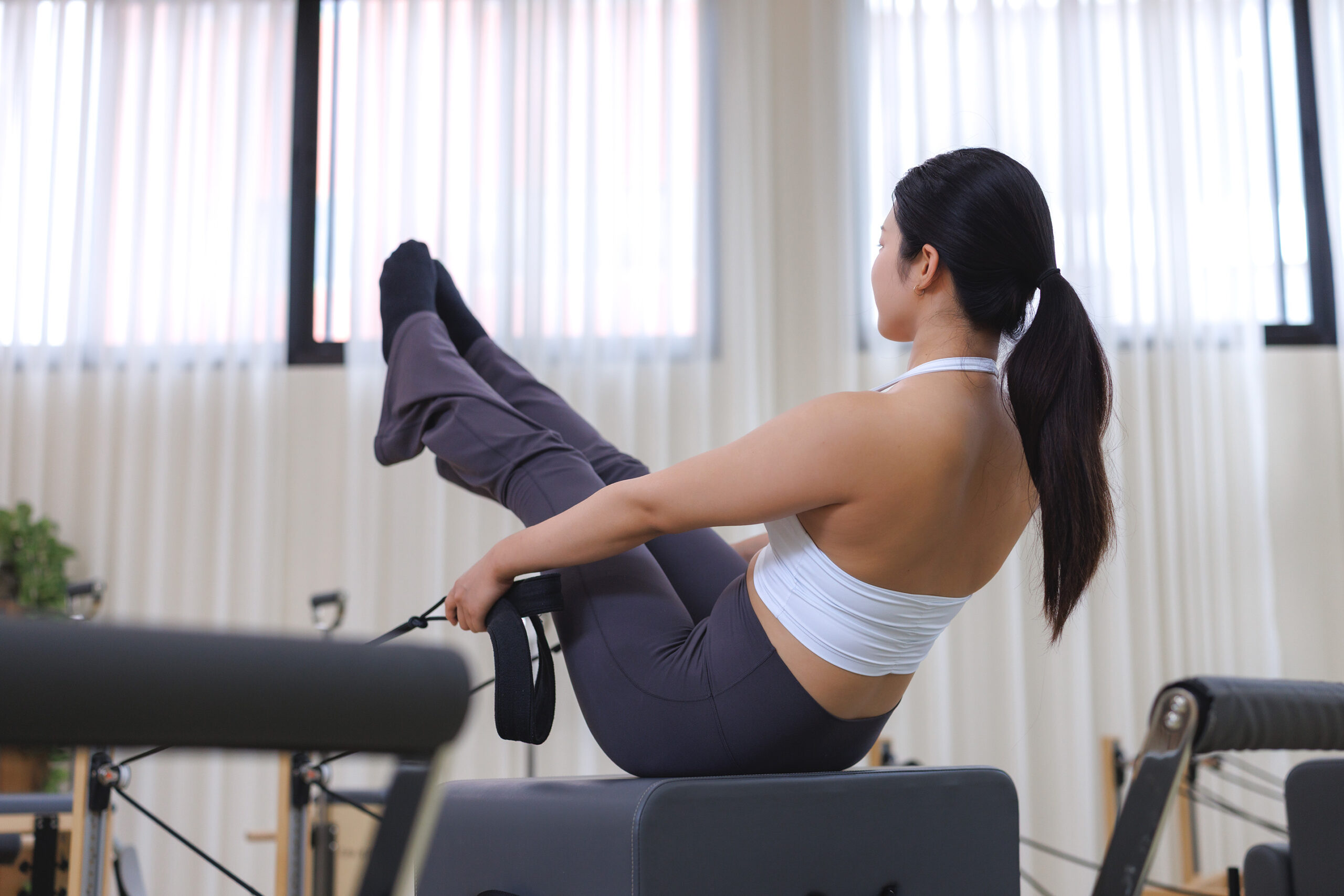 Chica entrenando con máquinas de pilates.
